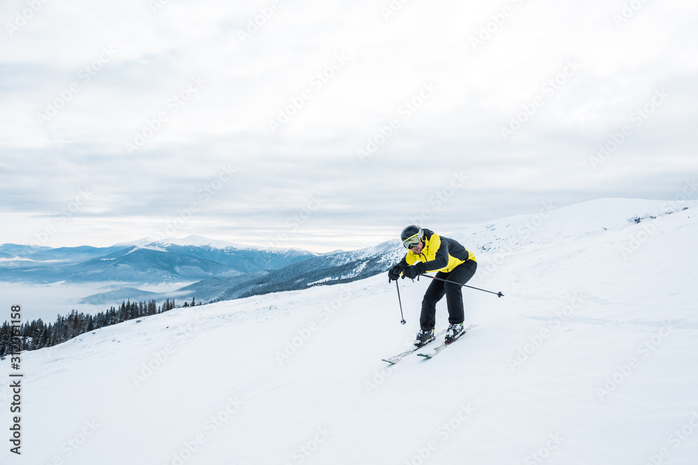 sportsman holding ski sticks and skiing on white slope in mountains