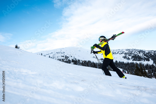 side view of skier walking with ski sticks on snow