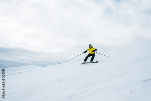 sportsman holding ski sticks and skiing on white slope