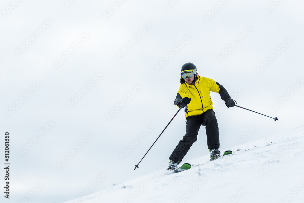 skier in helmet holding sticks and skiing on slope in wintertime skier in helmet holding sticks and skiing on slope in wintertime