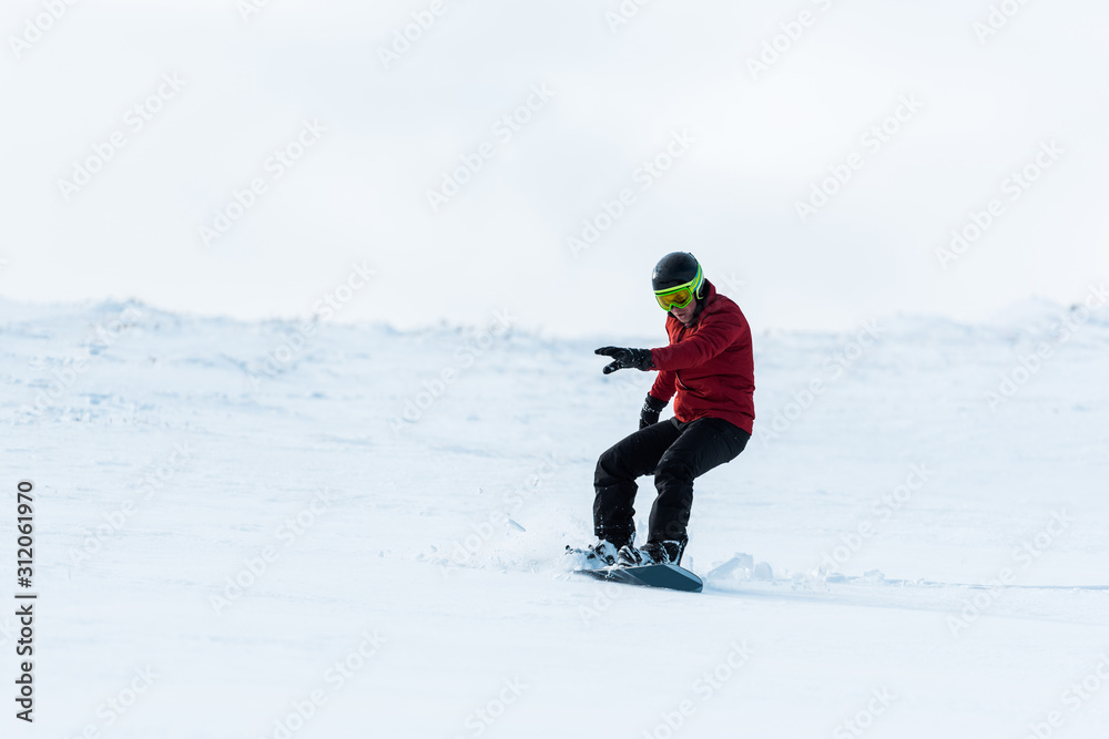 athletic snowboarder in helmet riding on slope outside athletic snowboarder in helmet riding on slope outside