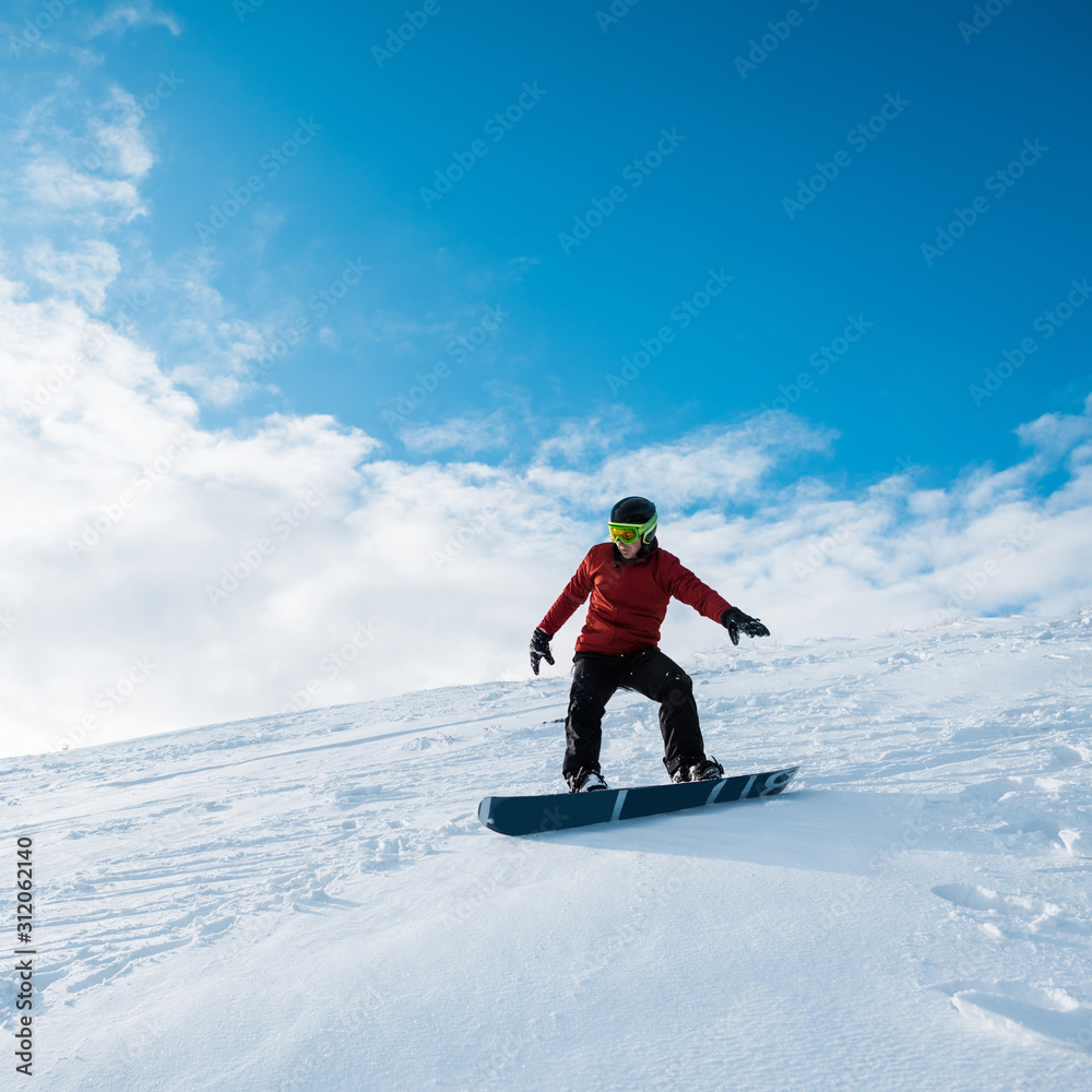snowboarder in helmet riding on slope against blue sky snowboarder in helmet riding on slope against blue sky
