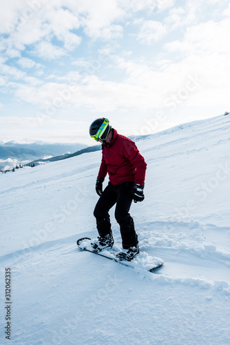 snowboarder in helmet riding on slope with white snow in wintertime