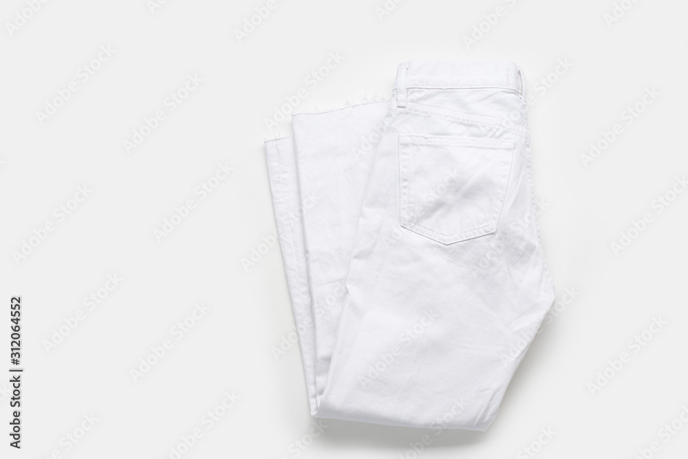 Folded white jeans on white background. Monochromatic flatlay Folded white jeans on white background. Monochromatic flatlay