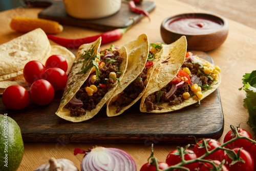 Fresh tacos with minced meat and vegetables on wooden table