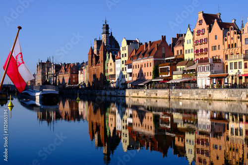 Colorful hanseatic city facades of historic houses close to the Motława river in Gdansk, a port city on the Baltic coast of Poland, in the foreground a polish flag