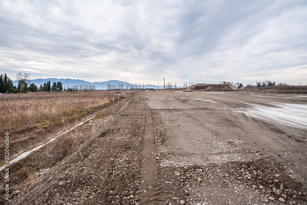 A dirt road leads to construction. A dirt road leads to construction.