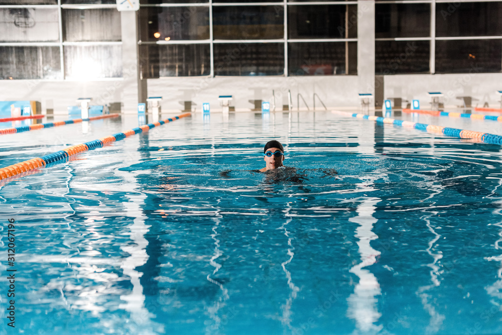 swimmer in goggles training in swimming pool