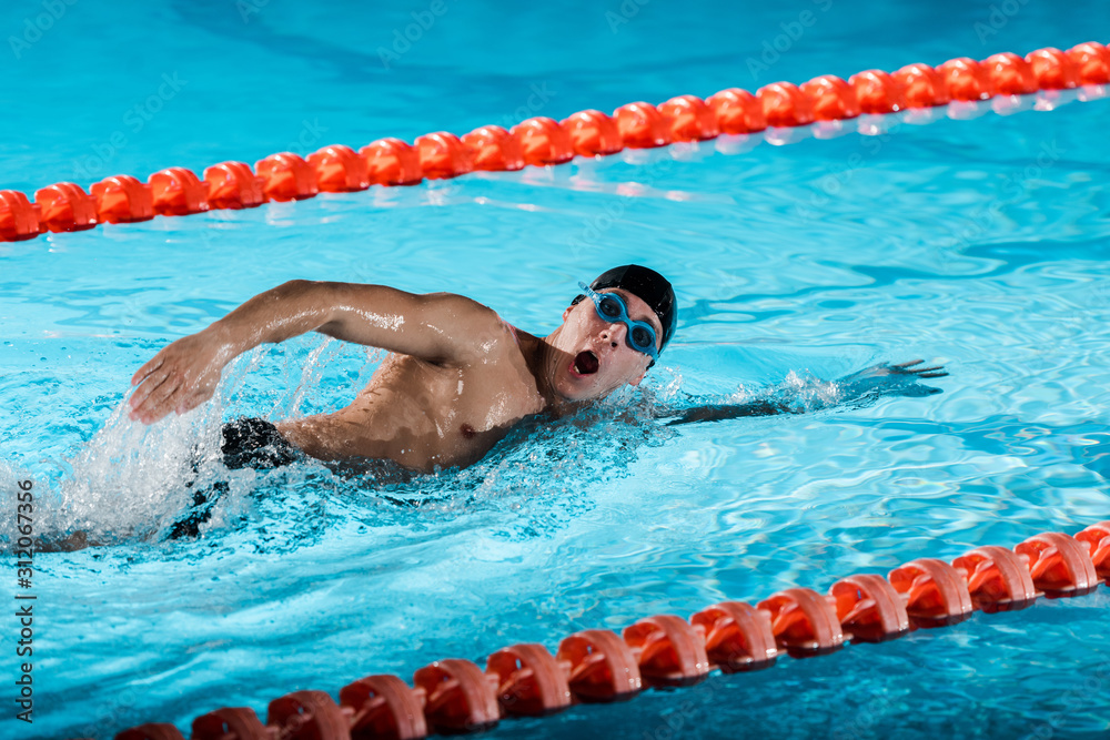 drops of water near swimmer with opened mouth training in swimming pool