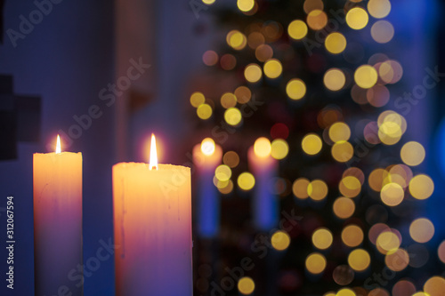 warmer, softer Kerzenschein und Lichterglanz im Altarraum einer Kirche mit Weihnachtsbaum