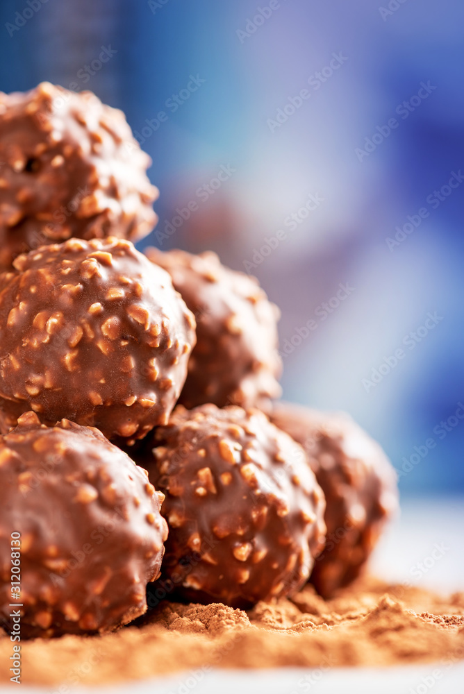 Pile of chocolate candies with nuts close-up, selective focus. Chocolate truffles lie on cocoa powder. Pile of chocolate candies with nuts close-up, selective focus. Chocolate truffles lie on cocoa powder.