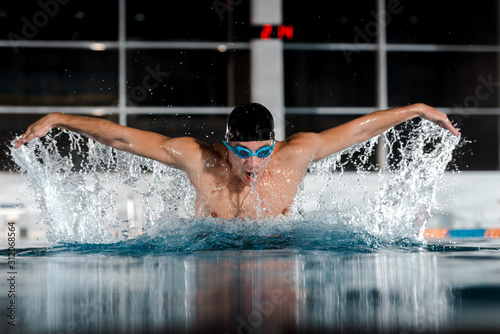 selective focus of sportsman swimming butterfly stroke in swimming pool
