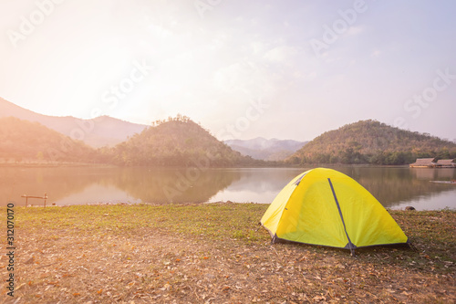 Tent Camping  beside the canal and mountains in the forest. Yellow tent on the green grass at Hoop Khao Wong Reservoir in the evening at Suphan Buri province  Thailand.
