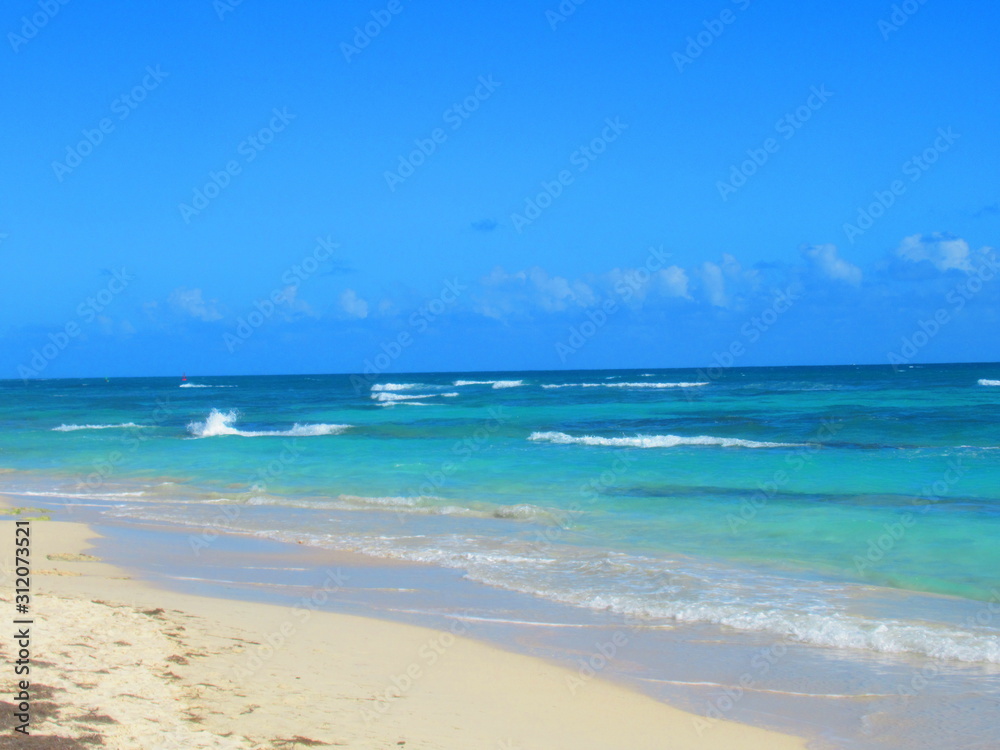 Une plage de sable blanc devant la mer turquoise avec des vagues