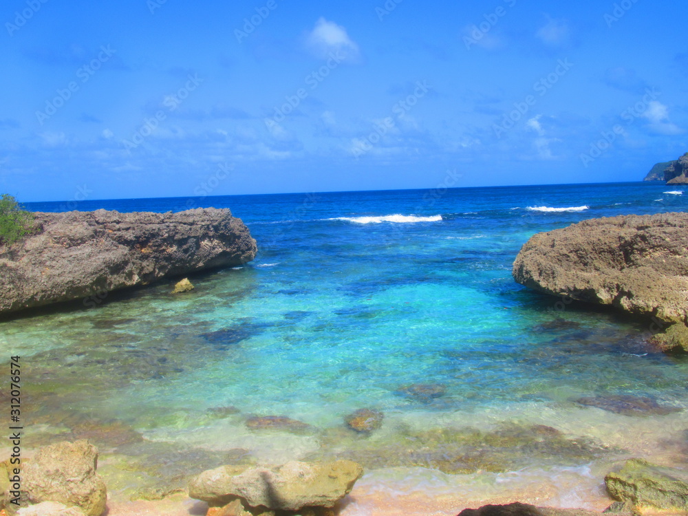 Une baie entourée  de rocher avec la mer turquoise