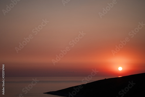 Half of sun was in horizon at the grey colour sea in the twilight. The sunset at the cape. Sunset horizon sea water landscape. Sunset sea horizon panorama. Orange sunset sea horizon view at sunset