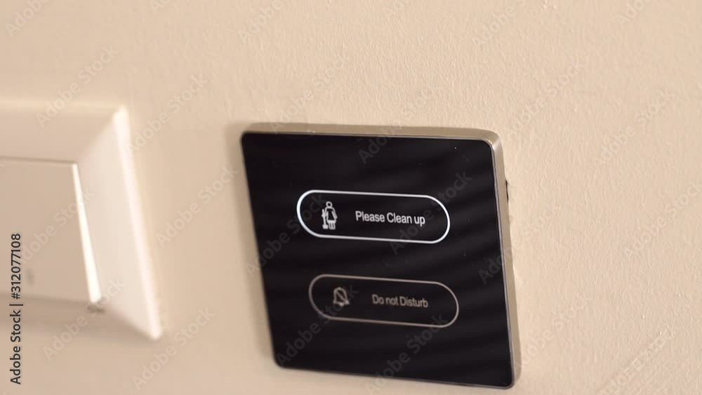 Close-up of the woman presses the button on the display with the sign Please clean up, on the door. Electronic sign Please clean up on the door in a modern hotel. Close-up of the woman presses the button on the display with the sign Please clean up, on the door. Electronic sign Please clean up on the door in a modern hotel.