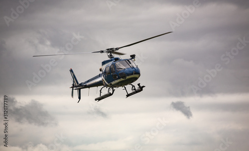 Fototapeta Naklejka Na Ścianę i Meble -  Blue helicopter in flight over gray sky