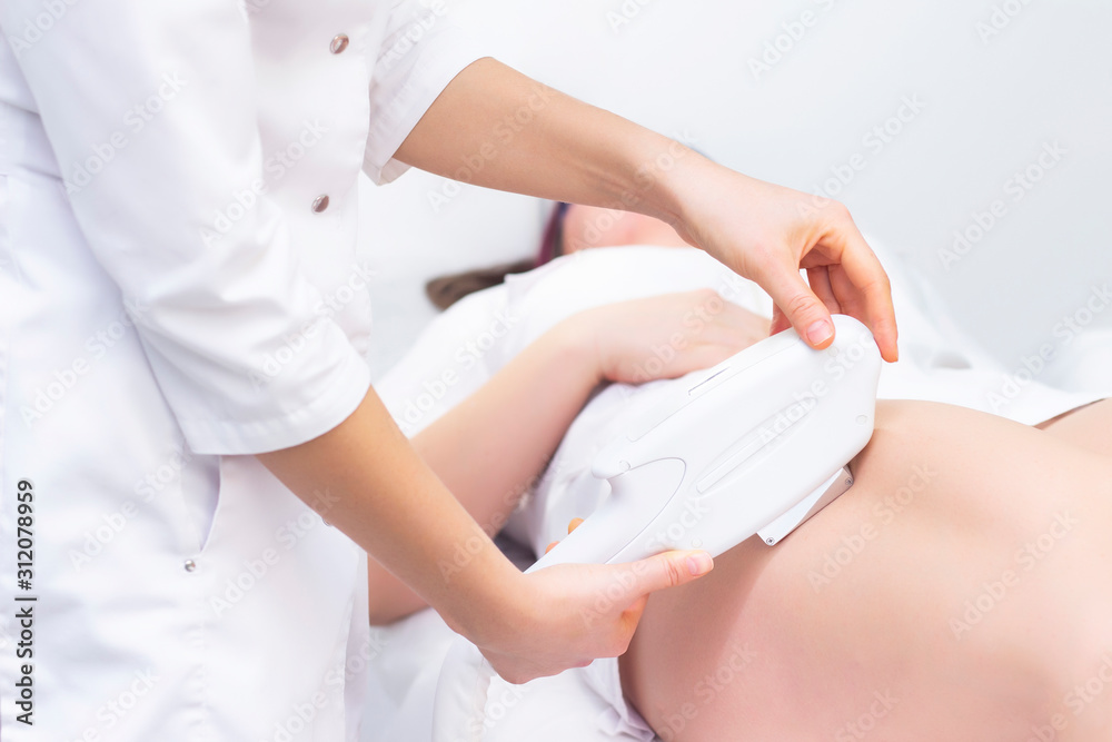 laser hair removal. the girl removes hair with a laser on her legs in a spa salon. the master holds a laser and removes hair. laser hair removal. the girl removes hair with a laser on her legs in a spa salon. the master holds a laser and removes hair.
