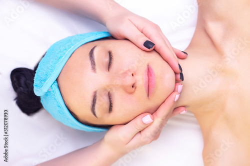 Young woman enjoying massage in spa salon. Face massage. Closeup of young woman getting spa massage treatment at beauty spa salon.Spa skin and body care. Facial beauty treatment.Cosmetology.