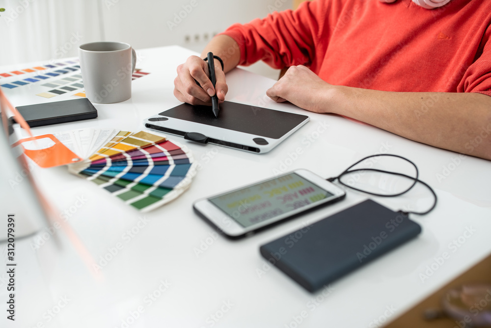 Hands of young freelance web designer holding stylus over graphics tablet screen Hands of young freelance web designer holding stylus over graphics tablet screen