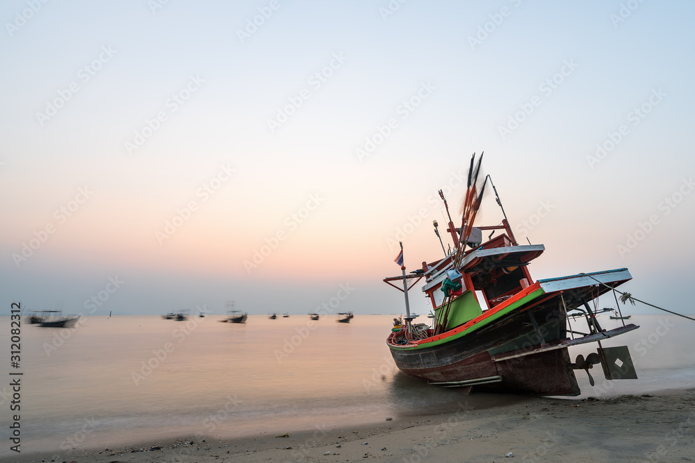 Beautiful seascape sunset with golden sunshine and fishing boat at the beach with copy space (long exposure)