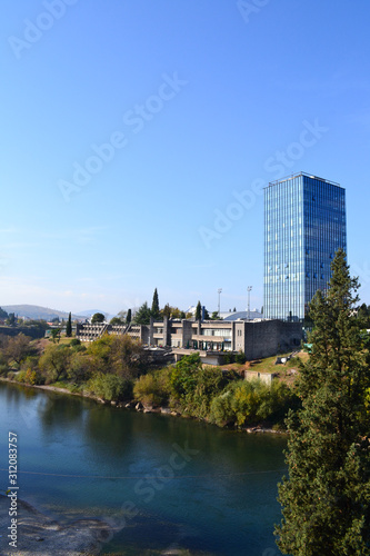 Skyscraper watching on blue clear river. Green cypress.Podgorica. Montenegro