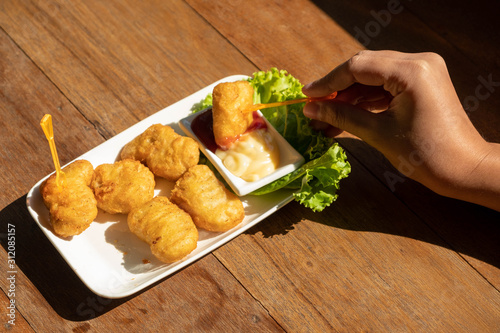 Eating chicken nuggets with two dipping sauce.