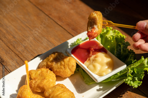 Eating chicken nuggets with two dipping sauce.