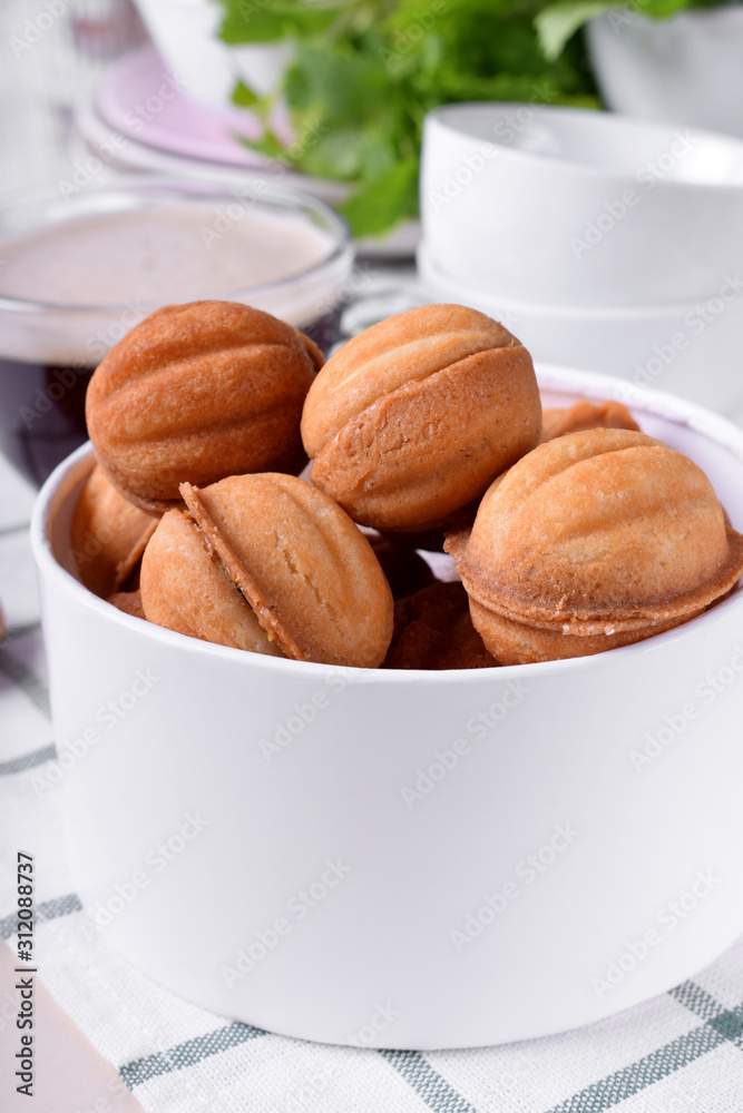 Walnut shaped cookies with condensed milk in a round box against white background Walnut shaped cookies with condensed milk in a round box against white background