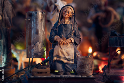 Christmas nativity scene represented with statuettes. Close-up of statuette of a woman at work.