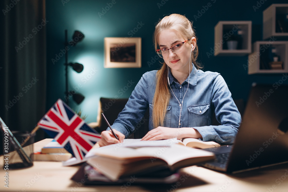 Portrait of young student posing at a desk in a living room while learning English Portrait of young student posing at a desk in a living room while learning English