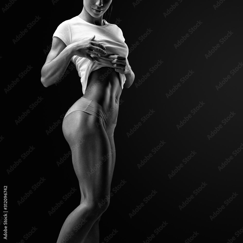Cropped black and white image of muscular young woman posing in sportswear Beautiful  sexy female slim tanned body. Stock Photo