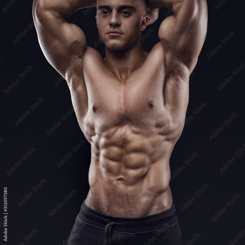 Fototapeta premium Sexy shirtless male model young bodybuilder posing over black background. Studio shot on black background.