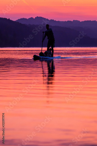 silhouette of a paddling man on a lake at sunset