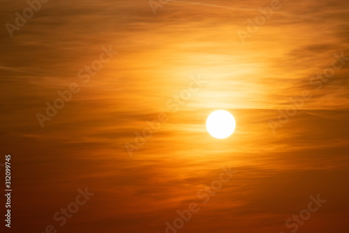 orange sunrise behind clouds