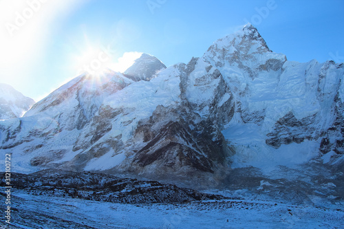 Sun rises right above West Ridge of Everest mountain in Himalayas. View from the slope of Kala Patthar mountain. Theme of travel in Nepal.