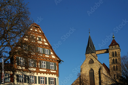 Um Vordergrund ein historisches Fachwerkhaus das ein Museum beherbergt im Hintergrund die Stadtkirche St. Dionys in Esslingen. photo