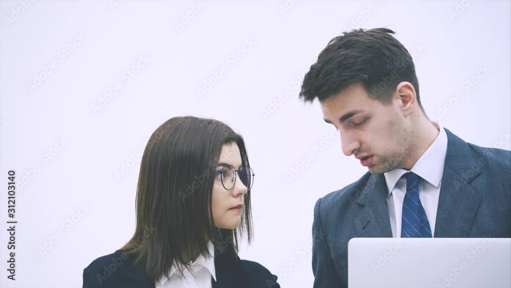 Handsome man is holding a laptop, explaining something to her partner. Handsome man is holding a laptop, explaining something to her partner.