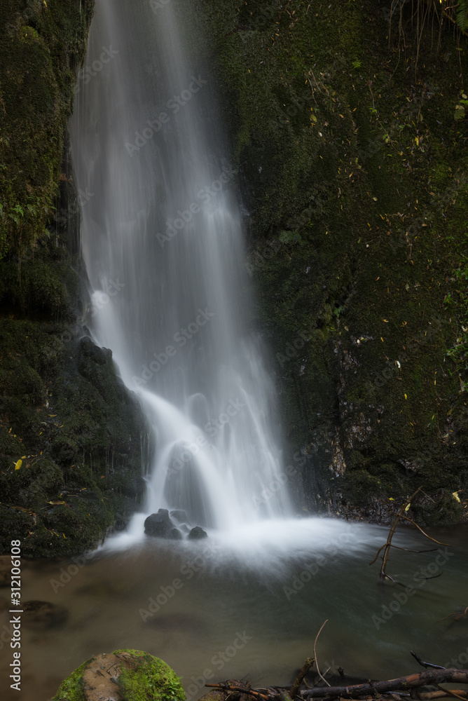 Long exposure photograph of the foot of a ten metres tall waterfall in McLean Falls Park, Bay of Plenty, New Zealand.