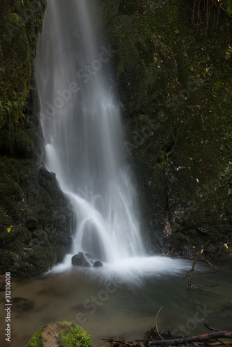 Long exposure photograph of the foot of a ten metres tall waterfall in McLean Falls Park, Bay of Plenty, New Zealand.