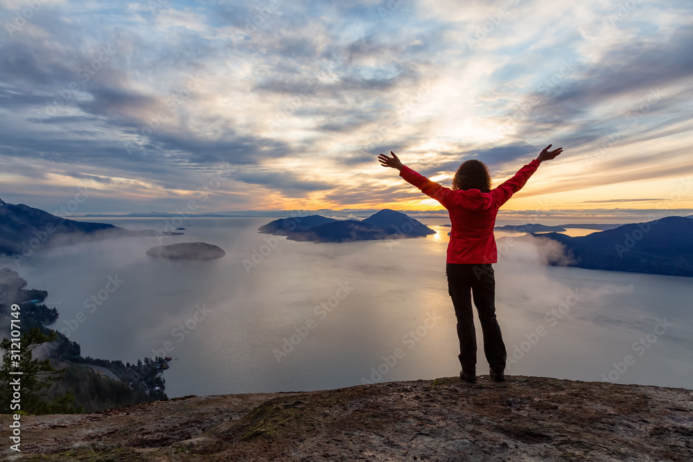 Adventurous Caucasian Girl sitting on top of a mountain during a colorful winter sunset. Taken on Tunnel Bluffs Hike, North of Vancouver, BC, Canada. Adventurous Caucasian Girl sitting on top of a mountain during a colorful winter sunset. Taken on Tunnel Bluffs Hike, North of Vancouver, BC, Canada.
