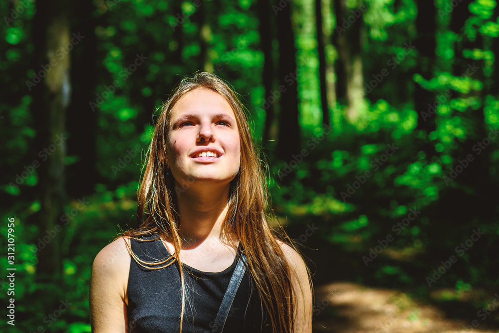 Outdoor portrait of young teenager brunette girl with long hair looking up in forest Outdoor portrait of young teenager brunette girl with long hair looking up in forest