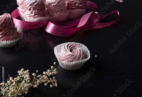 delicate berry marshmallows (zephyr) in front of a box of sweets on a dark for stand-up mealtable photo