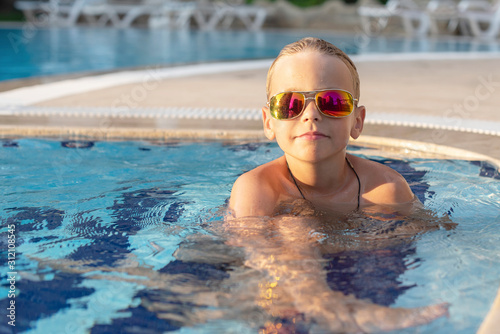 boy in sunglasses in the pool. concept of travel, summer, vacation, recreation and childhood