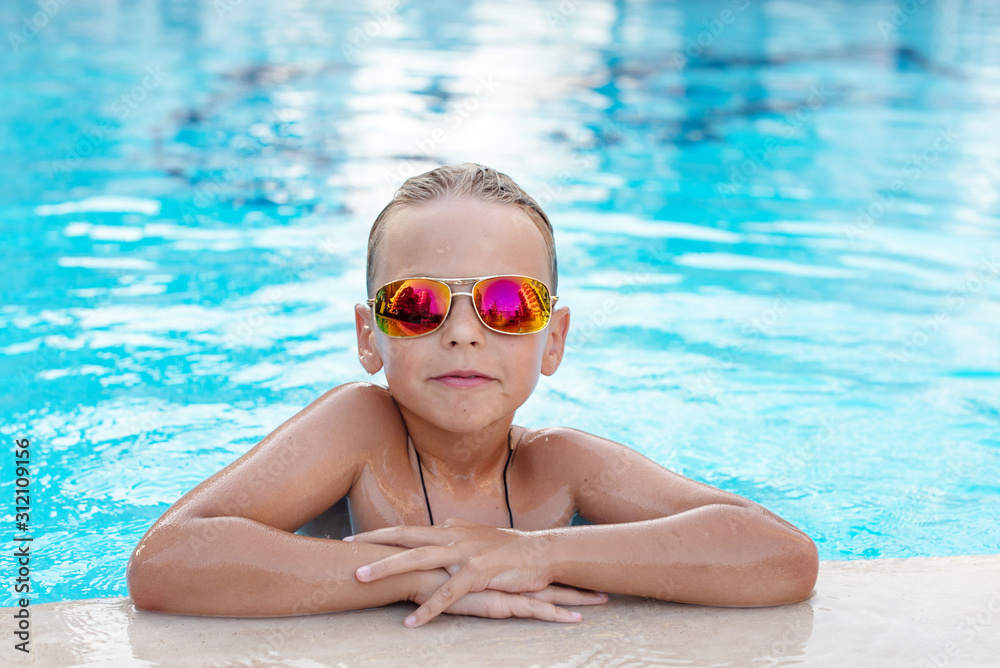 boy in sunglasses in the pool. concept of travel, summer, vacation, recreation and childhood