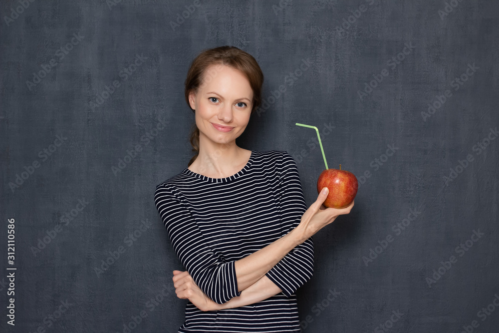 Portrait of happy young woman holding ripe apple with drinking straw Portrait of happy young woman holding ripe apple with drinking straw