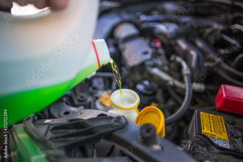 Topping up the green liquid in the car washer reservoir, for washing the glass