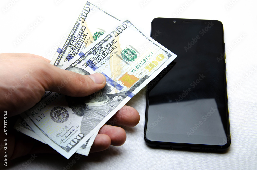 Dollars and smartphone on a white background. Dollars are on the smartphone. Dollars and smartphone on a white background. Dollars are on the smartphone.
