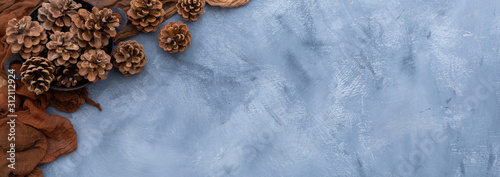 Tabletop scene with brown rag and pine cones on a grey grunge table. Flat layout scene with brown decorative elements. Copy space.